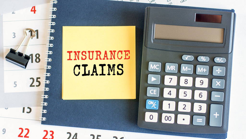 yellow piece of paper with the text insurance claims on the desk, selective focus